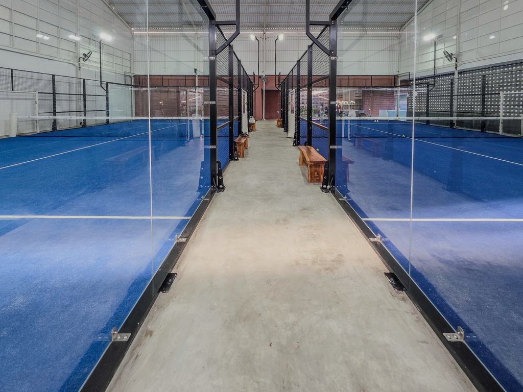 Row of glass-walled indoor padel courts