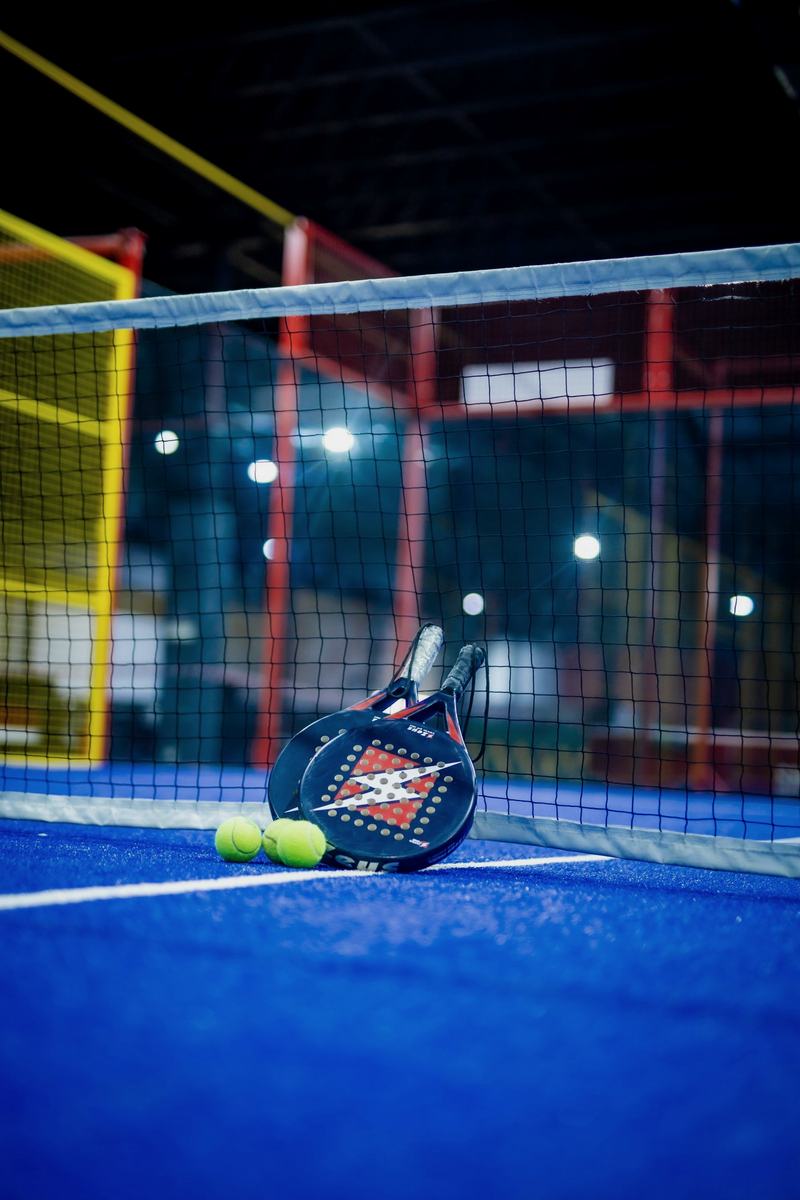 Padel racket and balls on a floodlit court