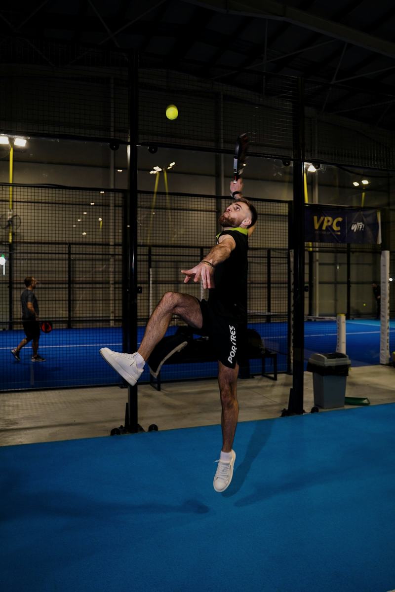 Player jumping for a smash on an indoor padel court